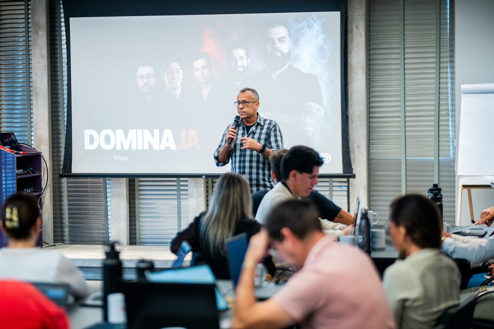 Plateia de empresários no evento DOMINA.IA com a marca projetada na tela